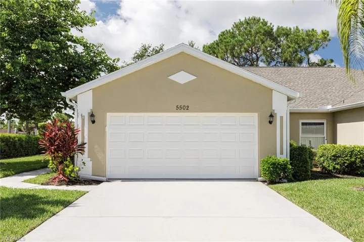 Ranch-style home with stucco siding, driveway, an attached garage, and a front yard