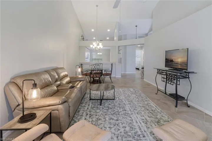 Living room featuring high vaulted ceiling, a chandelier, and a ceiling fan