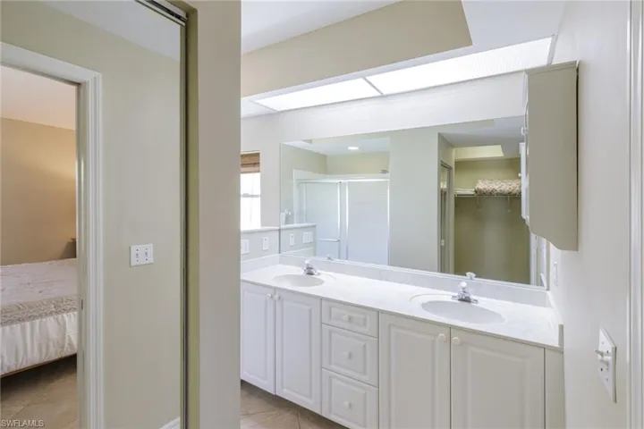 Full bathroom with a shower stall, double vanity, a walk in closet, ensuite bathroom, and tile patterned flooring