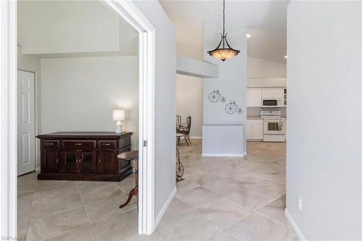 Corridor featuring light tile patterned floors and lofted ceiling