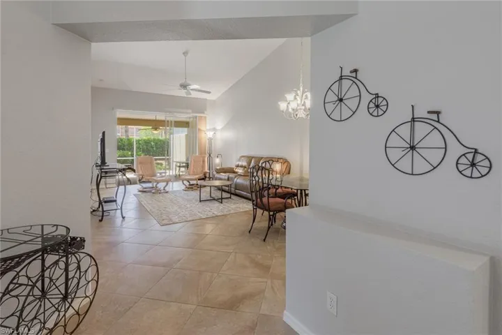 Hall with light tile patterned flooring, a chandelier, and high vaulted ceiling