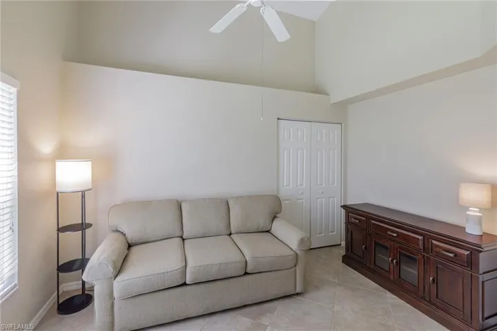 Living area featuring high vaulted ceiling, ceiling fan, and light tile patterned floors