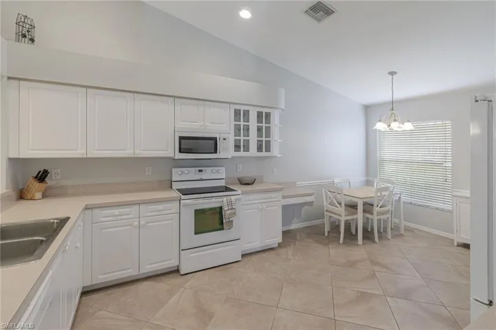 Kitchen with white appliances, white cabinetry, a chandelier, light tile patterned floors, and recessed lighting