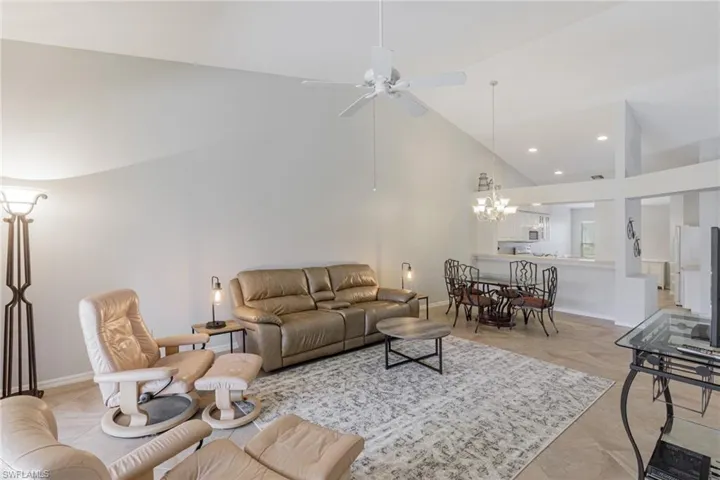 Living area with a chandelier, high vaulted ceiling, ceiling fan, and recessed lighting
