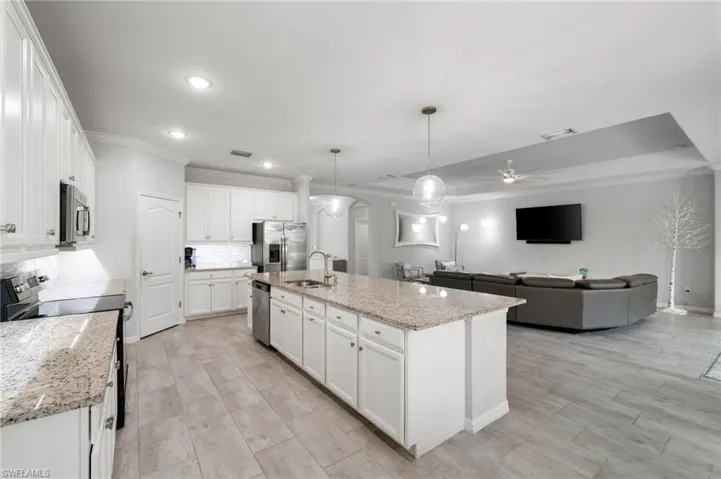Kitchen with appliances with stainless steel finishes, an island with sink, hanging light fixtures, sink, and ceiling fan