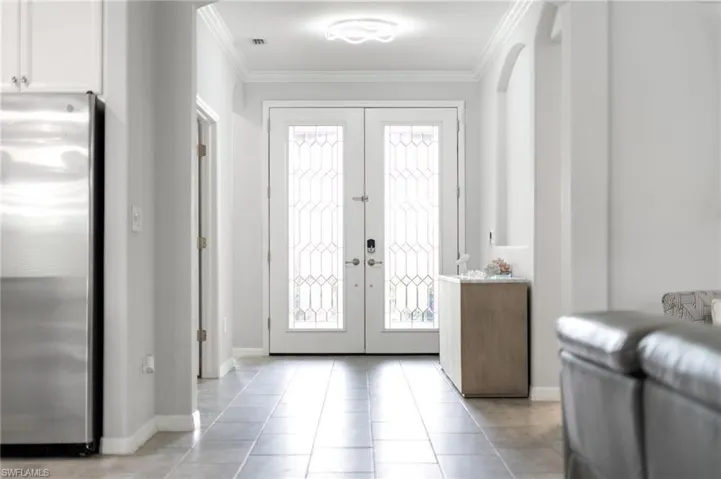 Entrance foyer featuring crown molding, french doors, and light tile patterned flooring