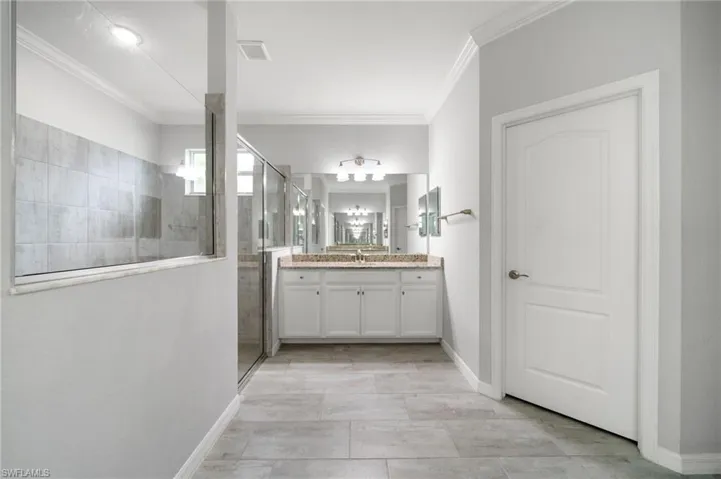Bathroom featuring a shower with door, crown molding, and vanity