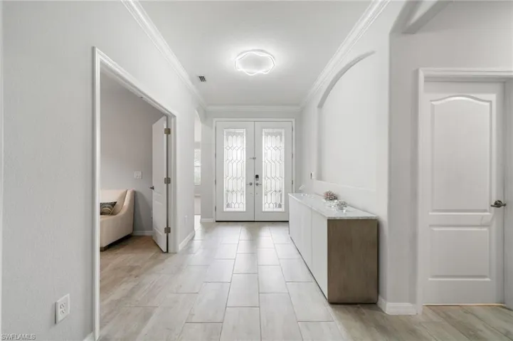 Entrance foyer with light hardwood / wood-style flooring, ornamental molding, and french doors