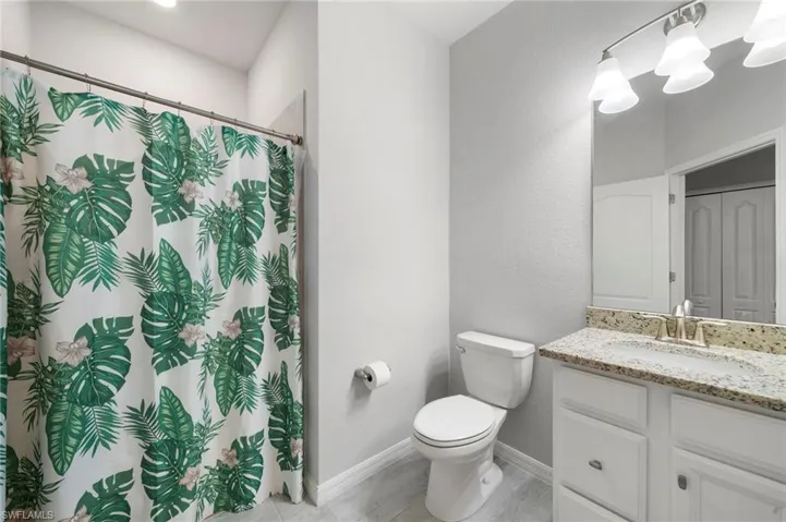 Bathroom featuring a shower with shower curtain, toilet, and vanity