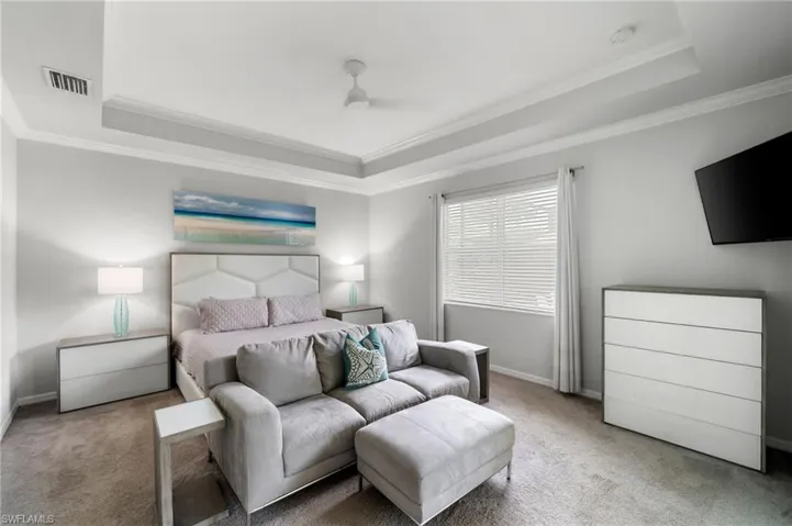 Carpeted bedroom featuring a tray ceiling and ornamental molding