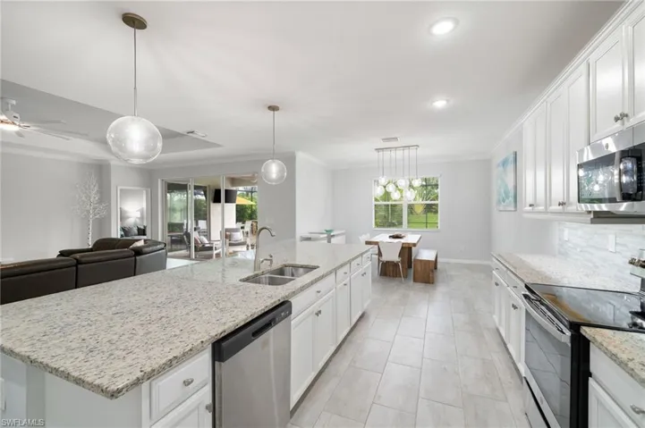 Kitchen featuring a kitchen island with sink, appliances with stainless steel finishes, sink, and white cabinets