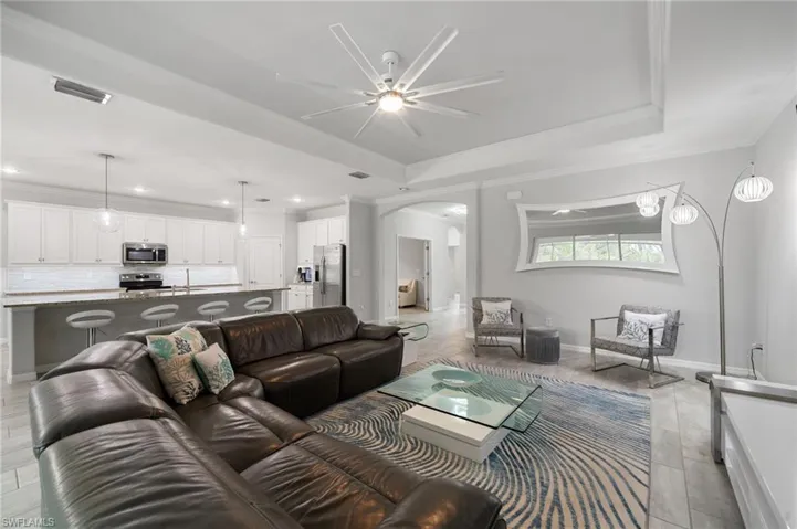 Living room with a tray ceiling, ceiling fan, sink, and ornamental molding