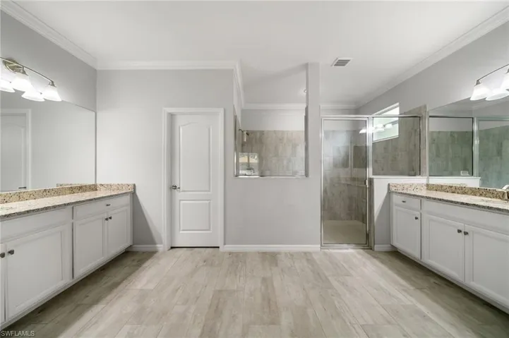 Bathroom with crown molding, vanity, hardwood / wood-style floors, and a shower with door