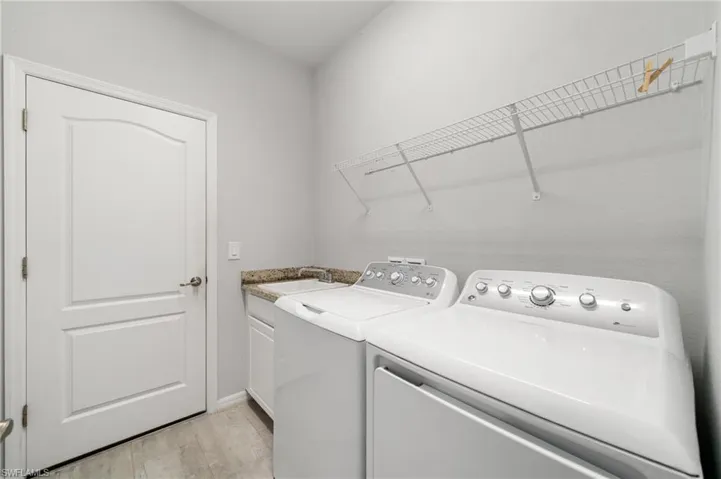 Laundry area featuring washing machine and clothes dryer, cabinets, and sink