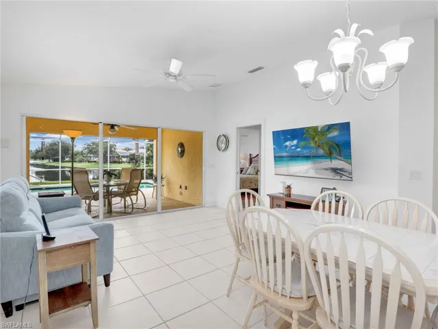 Dining room with ceiling fan with notable chandelier, lofted ceiling, and light tile patterned flooring