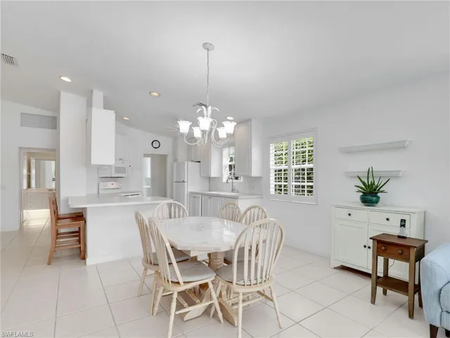 Dining space featuring light tile patterned floors, sink, and a notable chandelier