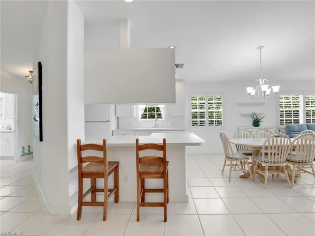 Kitchen with white cabinets, light tile patterned floors, and a kitchen bar