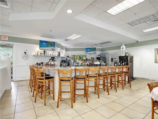 Kitchen featuring white cabinetry, a kitchen breakfast bar, light tile patterned floors, kitchen peninsula, and a tray ceiling