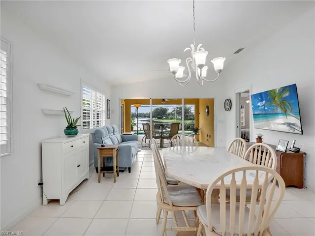Tiled dining space featuring lofted ceiling and a chandelier