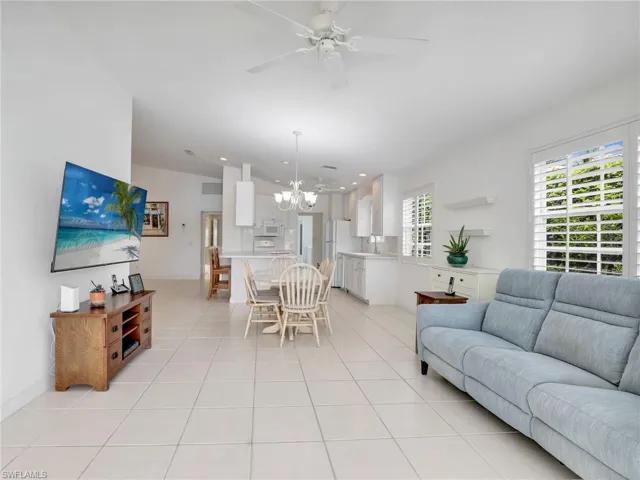 Tiled living room featuring sink and ceiling fan with notable chandelier