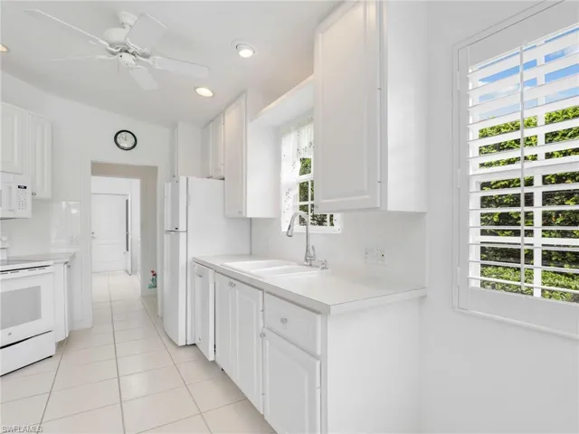 Kitchen featuring sink, white appliances, and white cabinetry