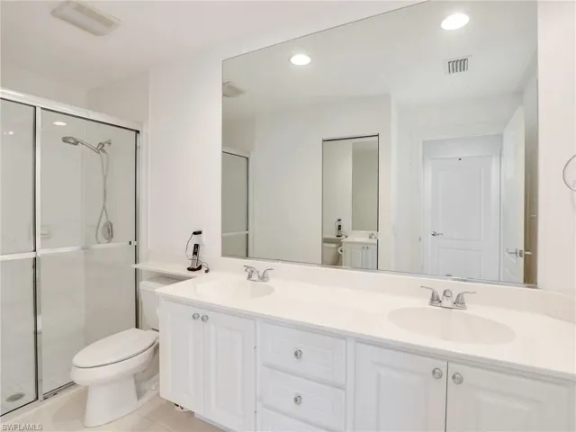 Bathroom featuring an enclosed shower, toilet, and vanity