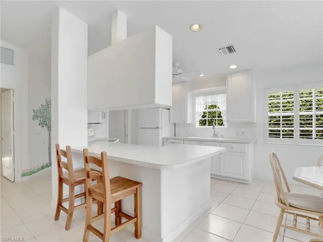 Kitchen featuring white cabinetry, range, light tile patterned floors, kitchen peninsula, and ceiling fan