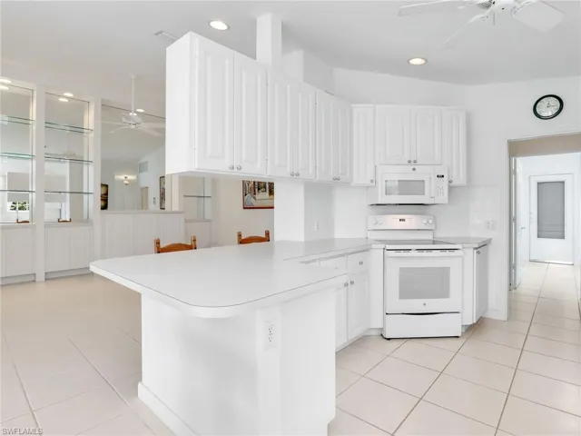 Kitchen with ceiling fan, white cabinets, kitchen peninsula, and white appliances
