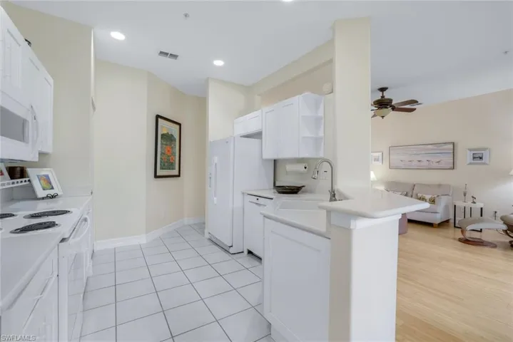 Kitchen featuring ceiling fan, white cabinets, light hardwood / wood-style floors, sink, and white appliances