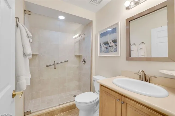 Bathroom with toilet, vanity, walk in shower, and tile patterned floors