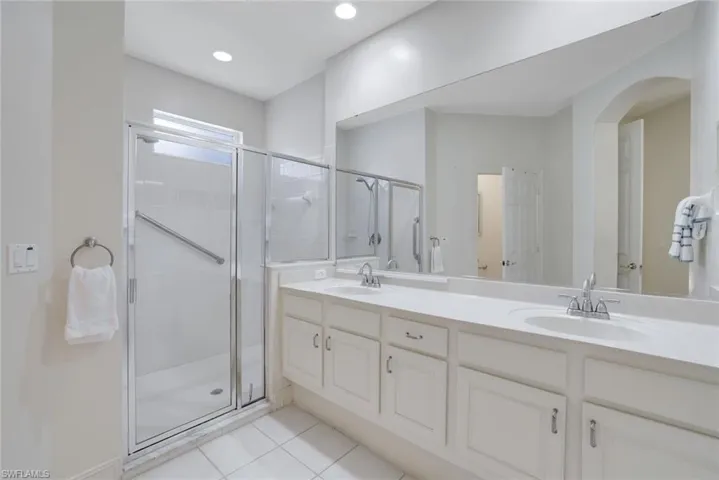 Bathroom with tile patterned floors, a shower with door, and vanity