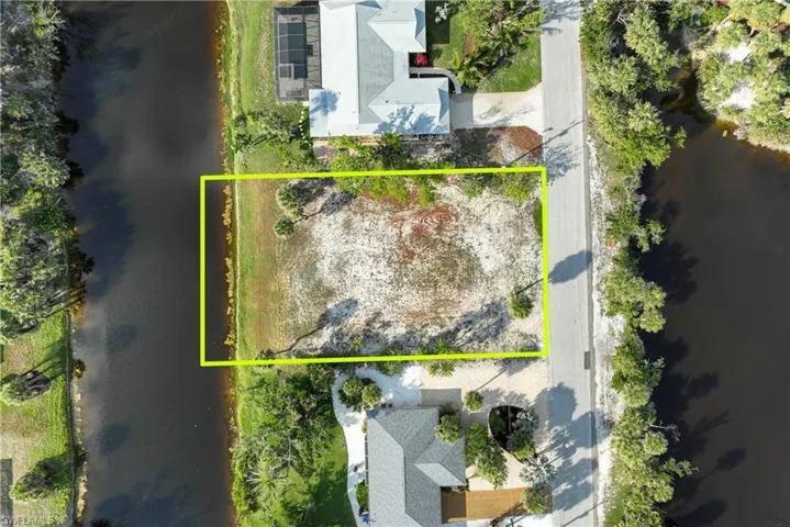 Aerial view of property and surrounding area with a nearby body of water and property boundaries highlighted