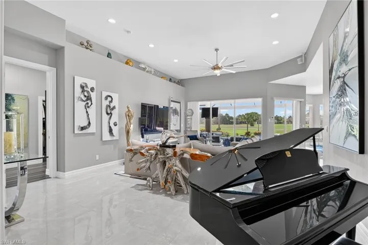 Spacious living area featuring polished porcelain tile flooring, high ceilings with recessed lighting, and a contemporary ceiling fan