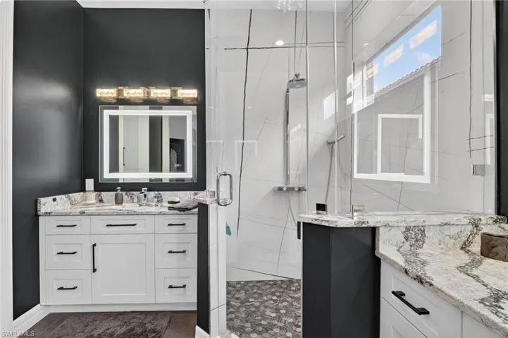 Primary Oasis featuring a frameless glass shower enclosure, a white shaker vanity with illuminated LED heated, anti-fog, dimmable, tone adjustable mirrors