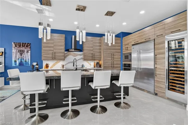 Kitchen boasting a large island with plenty of seating featuring gold standard premium appliances