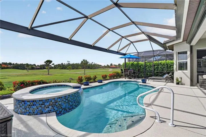 Screened lanai featuring lounging and entertainment area, a freeform pool with integrated spa and mosaic tile accents and breathtaking golf course views