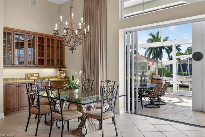 Dining area featuring hanging lights, light tile patterned floors, a high ceiling, and crown molding