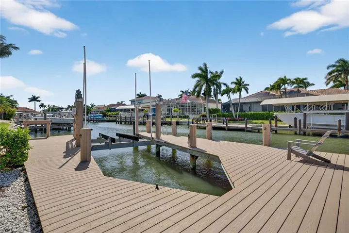 Dock featuring boat lift, a water view, and a residential view