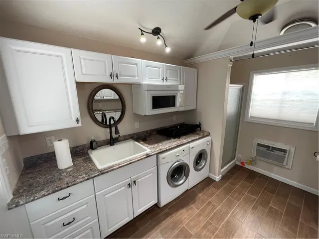 Laundry area with washing machine and clothes dryer, a wall mounted AC, a ceiling fan, and dark wood-style floors