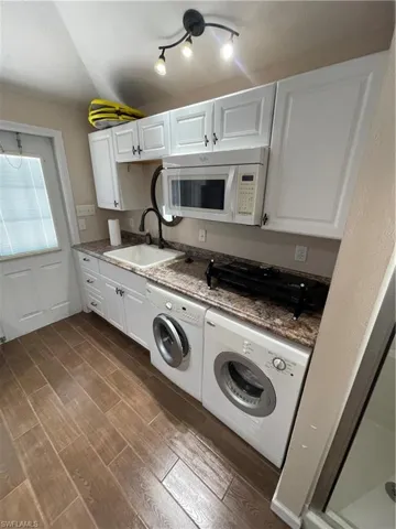 Washroom featuring washing machine and clothes dryer and dark wood-style floors
