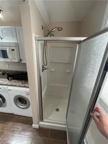 Full bathroom with washer / clothes dryer and a stall shower