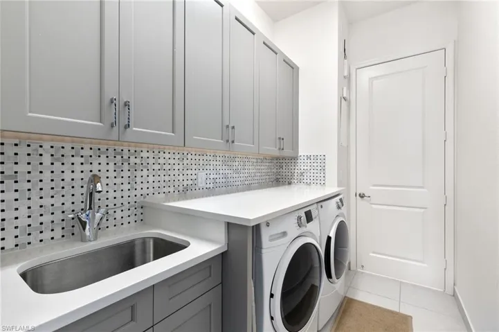 Laundry area featuring light tile patterned flooring, cabinet space, and washer and clothes dryer
