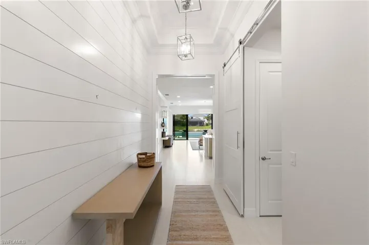 Entryway featuring wooden walls, crown molding, tile patterned floors, and a barn door
