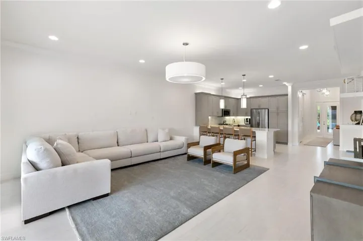Living room with crown molding, recessed lighting, a sunroom, and a water view