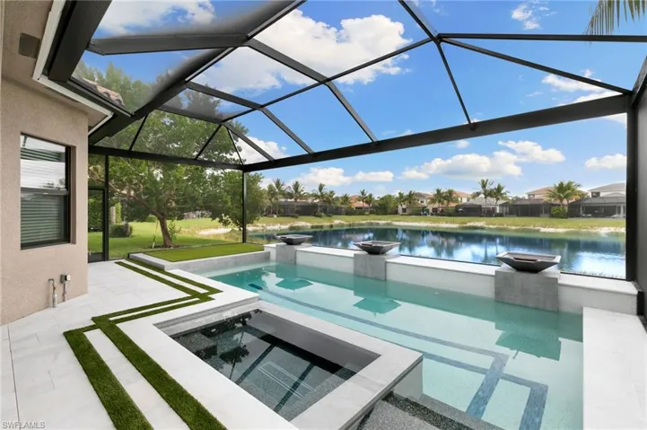 View of swimming pool with a lanai, a sunroom, a water view, a patio, and a pool with connected hot tub