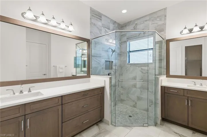 Bathroom featuring two vanities and a stall shower
