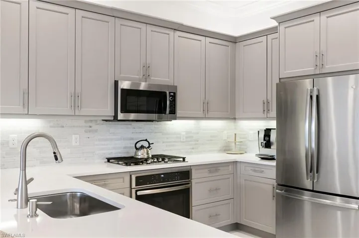 Kitchen featuring tasteful backsplash, a peninsula, a kitchen bar, crown molding, and appliances with stainless steel finishes