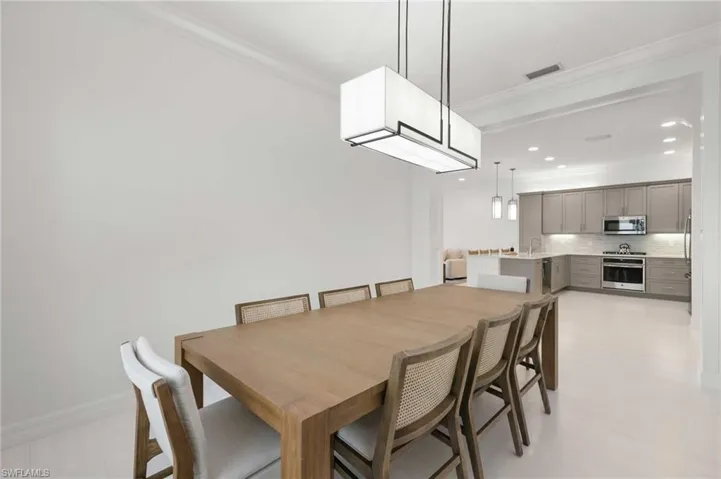 Kitchen featuring gray cabinetry, crown molding, decorative light fixtures, open floor plan, and stainless steel dishwasher