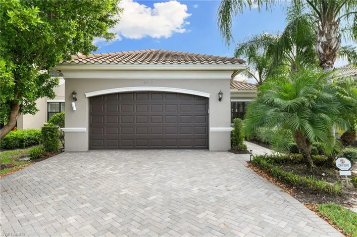 View of front of property with decorative driveway, a tiled roof, and stucco siding