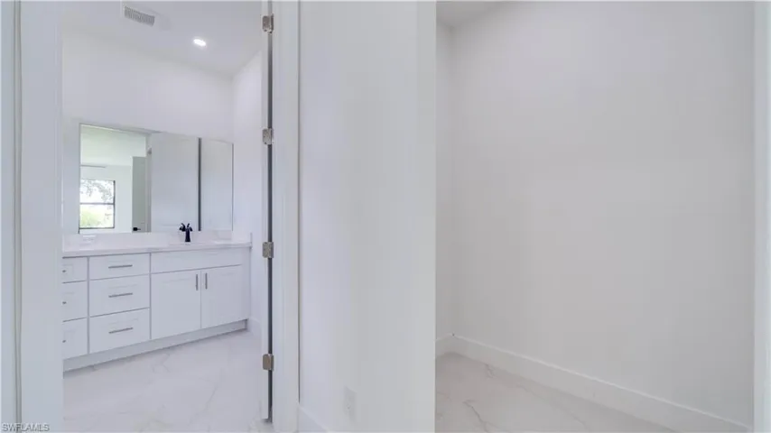 A view leading to the en-suite from the primary suite hallway. One of the two walk-in closets is on the right.